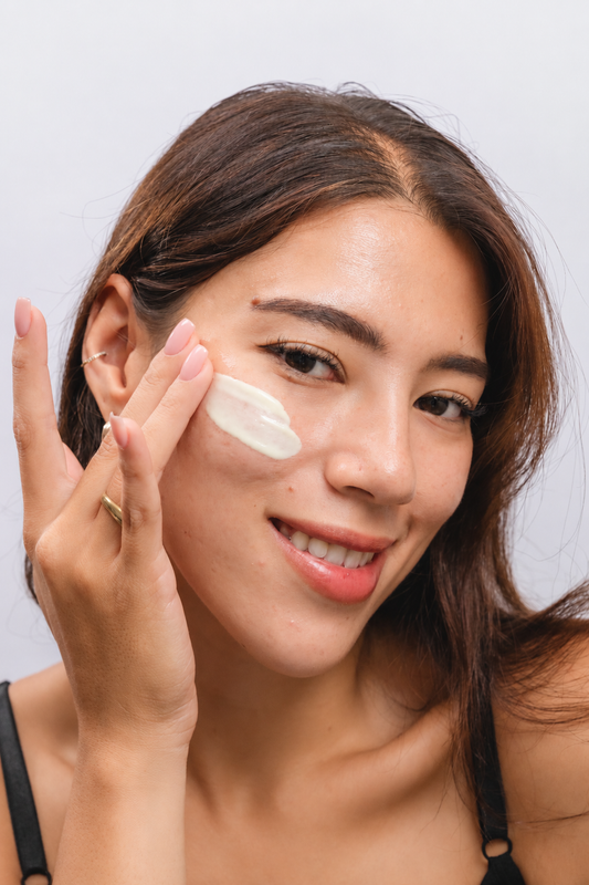 Woman with acne-prone skin applying lightweight sunscreen as part of her daily skincare routine.